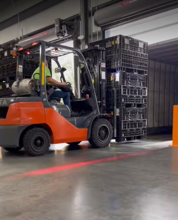 Man operating a fork truck loading assembled parts in warehouse