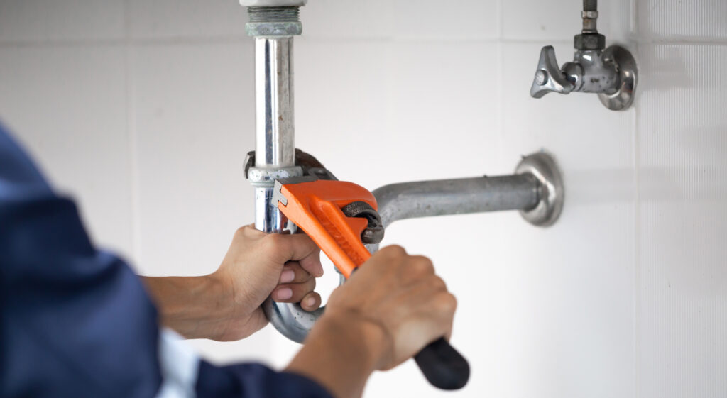 Facilities Support Contractor working on plumbing.